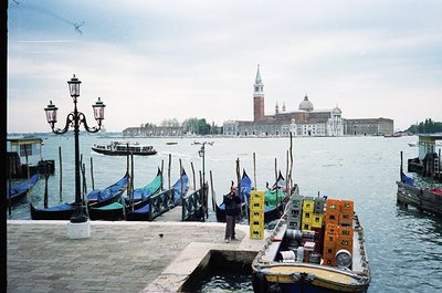 Classic Venetian canal scene with traditional *gondolas* moored along a stone quay. The iconic **San Giorgio Maggiore** churc...