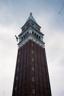 Tall brick clock tower with ornate copper dome, featuring rectangular windows and decorative stonework. Likely a historic Eur...