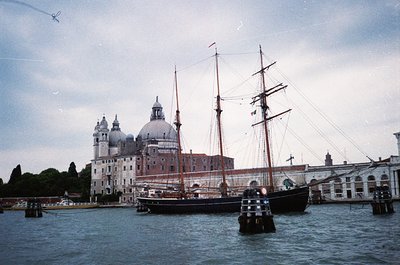 Historic sailing ship docked at Venice’s San Giorgio Maggiore island, with the island’s domed church and brick church façade ...