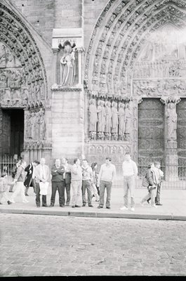 Romanesque-style cathedral façade featuring intricate stone carvings, arched doorways, and a central relief of a robed figure...