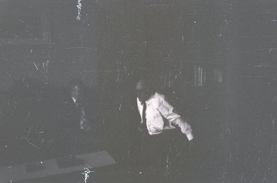 Vintage black-and-white photo of two figures in motion, likely mid-19th to early 20th century. Blurred motion suggests dynami...