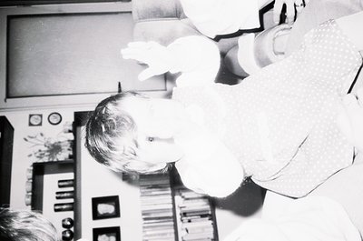 Vintage black-and-white photo of a child peeking from behind a cardboard cutout of a spaceship or rocket, likely from the 196...