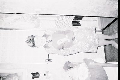 Mid-century modern hotel room interior, captured from a low-angle perspective. A woman in a sleeveless dress sits on a curved...