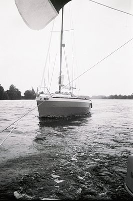 Classic 1970s sailboat (P4-S370 hull) anchored in calm waters, captured in black-and-white. Clean lines, single mast, and min...