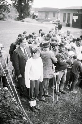 Black-and-white photo of a public gathering in an outdoor setting, likely a 1970s-1980s Eastern Bloc country. A diverse crowd...