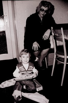 Black-and-white indoor portrait of a woman (mid-40s+) and young boy (early childhood) in a modestly furnished room, likely mi...