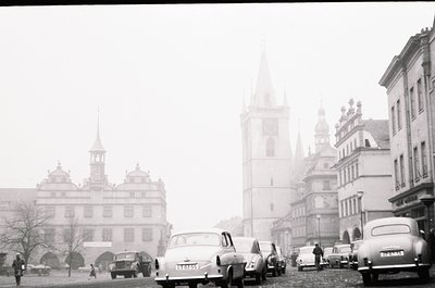 Mid-20th century European cityscape with misty fog obscuring details. Classic Baroque-style buildings with gabled roofs and o...