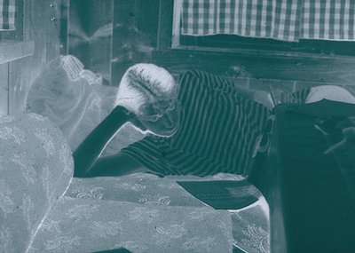 Vintage black-and-white portrait of an elderly woman resting her head on a marble or stone surface, likely a window ledge or ...