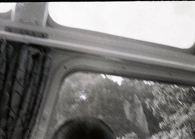 Close-up of a vintage car’s rearview mirror and door frame, showing wear and motion blur. Likely mid-20th century automotive ...