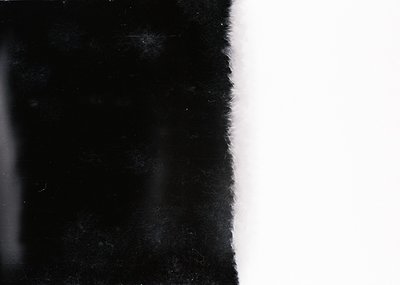 High-contrast monochrome image of a **damaged or aged photograph** showing partial **textured paper** and **fading content**....