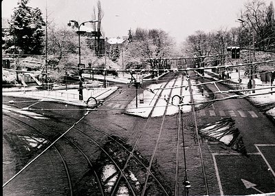A vintage aerial view of a tram network intersecting with a canal in an urban setting. Tram tracks converge at a central junc...