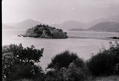 Black-and-white coastal scene featuring a fortified island structure surrounded by calm waters, likely a historic watchtower ...