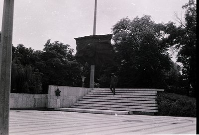 Monumental Soviet-era memorial with a hammer-and-sickle emblem on a concrete base, flanked by a large abstract stone relief. ...