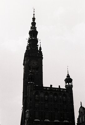 Gothic-style clock tower with ornate spire and intricate stonework, likely part of a historic European cathedral. Symmetrical...