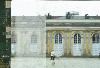 Vintage sepia-toned photo of a grand neoclassical building with arched windows and cream/yellow façade, likely mid-20th centu...