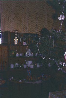 Vintage holiday display featuring a wooden shelf adorned with silverware, ceramic teapots, and a tiered cake stand with festi...