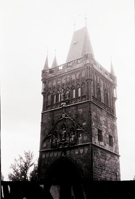 Historic stone tower with Gothic Revival architecture, featuring ornate carvings and a pointed spire. The central relief depi...
