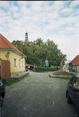 Vintage street scene featuring Soviet-era architecture: yellow-painted brick house with red-tiled roof, cobblestone courtyard...