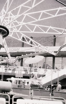 Vintage amusement park ride with "Rodeo" branding, featuring a rotating, tiered structure and metal guardrails. A child in a ...