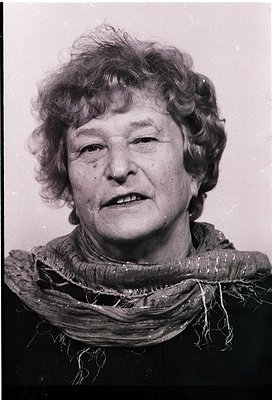 Portrait of an elderly woman in mid-profile, wearing a textured scarf. Mid-20th century style with matte black background. Li...