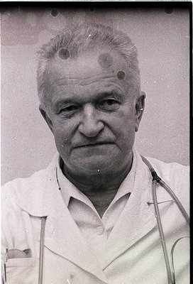 Portrait of an elderly man in a white lab coat, likely a physician, with three small circular scars on his forehead. Mid-20th...