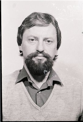 Portrait of a man with a full beard and mustache, wearing a collared V-neck sweater. The style suggests a mid-20th century lo...