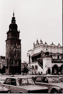 Historic 1960s black-and-white photo of Kraków’s **St. Mary’s Basilica** and its towering clock spire, flanked by Baroque-sty...