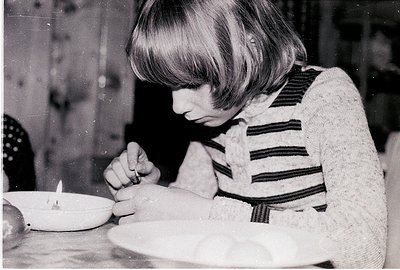 Young girl in 1960s-70s striped sweater meticulously decorating a round cake with icing, likely for a birthday or celebration...