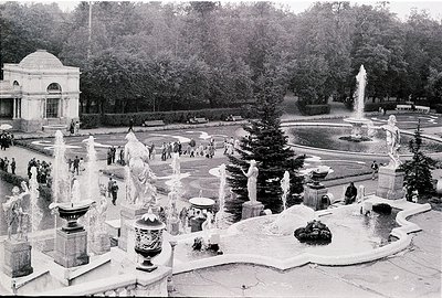 Grand classical fountain complex with ornate sculptures and cascading water in a public park. Neoclassical pavilion in backgr...