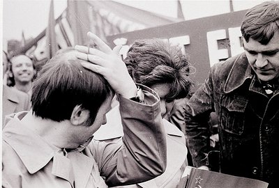 Intimate black-and-white moment of three men in close emotional exchange, likely 1960s–1970s Eastern Bloc. Foreground figure ...