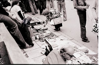 Street market scene featuring vendors selling fresh fish on pavement tables, likely in a European coastal city. Mid-20th cent...