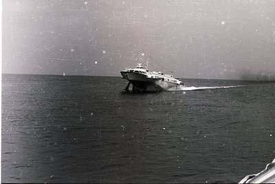 Vintage black-and-white photo of a high-speed passenger ferry cutting through choppy waters, likely mid-20th century. Sleek h...