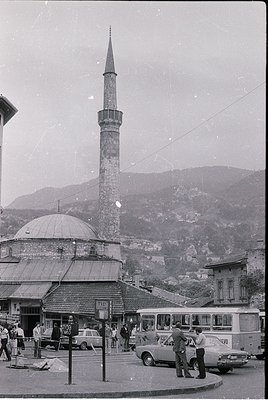 Mid-20th century street scene featuring a prominent Ottoman-style minaret and domed mosque (). Surrounding buildings exhibit ...