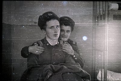 Vintage black-and-white photo of two individuals in military uniforms, likely Soviet-era (1940s–1950s). Uniforms feature peak...