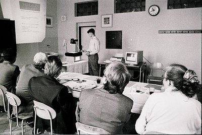 Early 1980s classroom featuring early computer training. Instructor demonstrates a bulky CRT terminal while seated students e...
