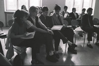 Classroom scene featuring students in 1970s-era school uniforms—girls in knee-length dresses, boys in suits—engaged in an exa...