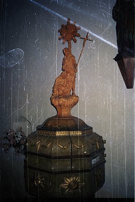 Religious wooden statue of a robed figure holding a sunburst halo and cross, mounted on an ornate gilded pedestal. Likely a 1...