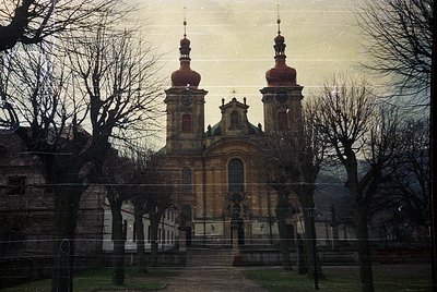 Baroque-style church with twin domed towers and ornate façade, framed by bare winter trees. Likely Eastern European architect...