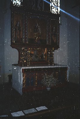 Ornate wooden iconostasis with religious iconography, featuring five painted panels depicting saints and biblical scenes. Mar...
