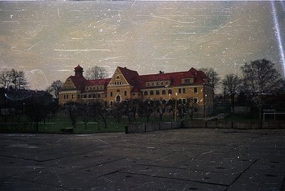 Vintage sepia-toned photograph of a grand, symmetrical **Art Nouveau-style building** with red-tiled roofs and arched windows...