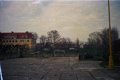 Vintage urban scene through a fogged window, showing a yellow brick building with arched windows and a red-tiled roof. Empty ...