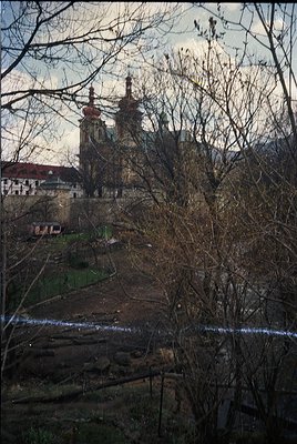 Baroque-style church with twin towers and ornate façade framed by winter trees. Urban landscape with residential buildings in...