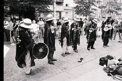 Street scene featuring a traditional folk band in traditional attire, likely Bulgarian. Musicians play accordions, drums, and...