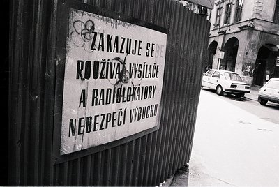 Czech warning sign prohibiting fireworks and radio detectors near exits for safety. Urban street scene with vintage car, like...