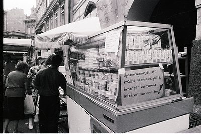 Street-side ice cream stall in urban setting, likely Eastern Europe, 1960s–70s. Handwritten sign warns of hygiene risks ("Upo...