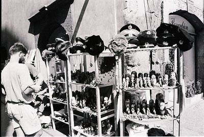 Vintage street vendor stall showcasing military hats and stuffed animal figurines in glass display cases, likely mid-20th cen...