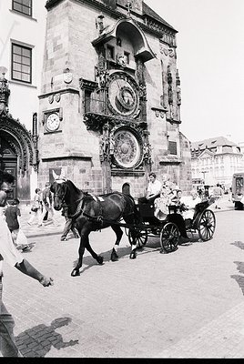 Historic horse-drawn carriage passing Prague’s Astronomical Clock tower (Orloj), 15th-century Gothic architecture with mediev...