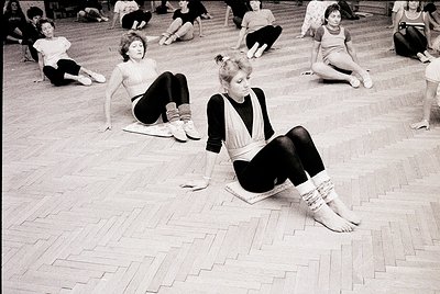Classical ballet training session in a studio, mid-20th century. Dancers in leotards and tights practice floor exercises on p...