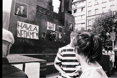 Black-and-white protest scene featuring a memorial wall with handwritten sign reading "HAVLA NEDÁME" (Czech/Slovak for "We Wo...