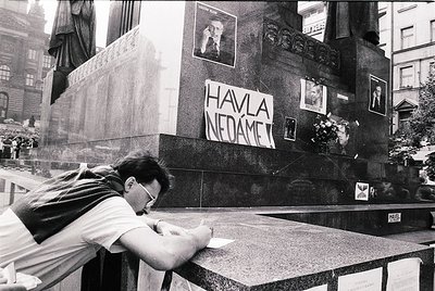 A man in a urban setting signs a memorial wall with the slogan "Havláč nedáme" (We Won’t Give Up Havlíček) in Prague, likely ...
